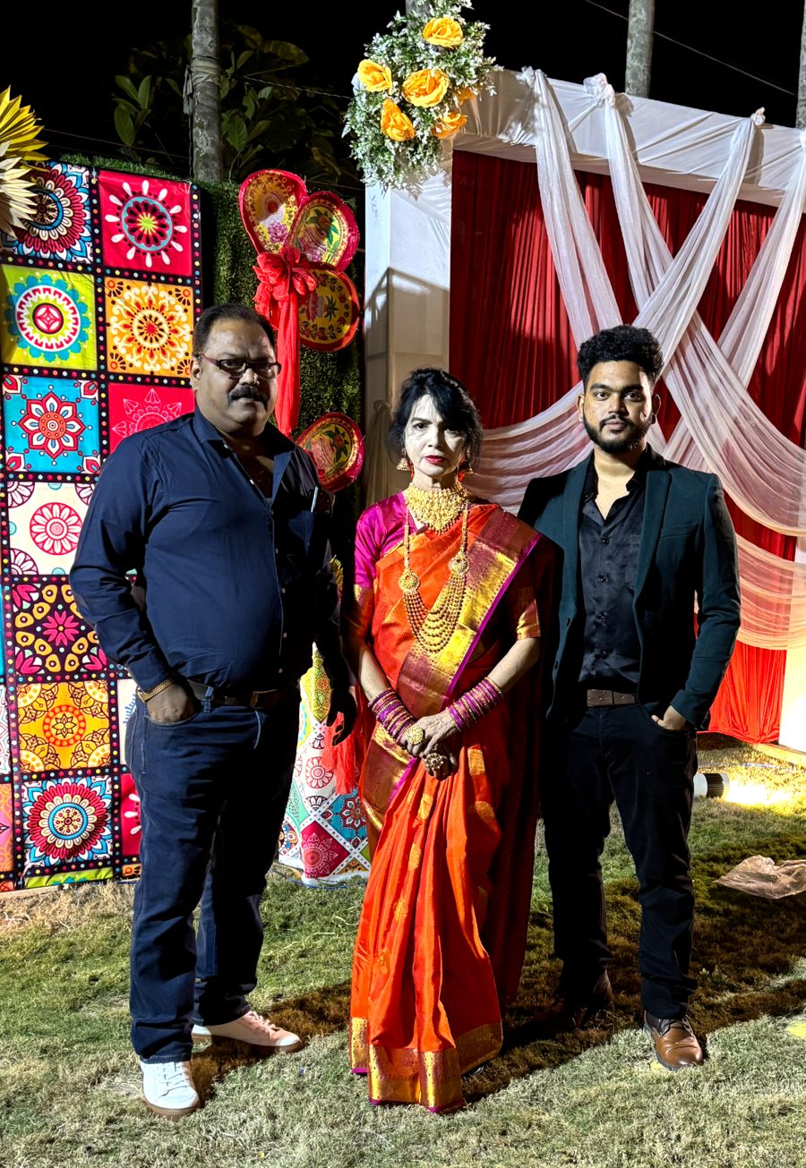 Jai with family at a wedding, standing in front of a colourful floral backdrop